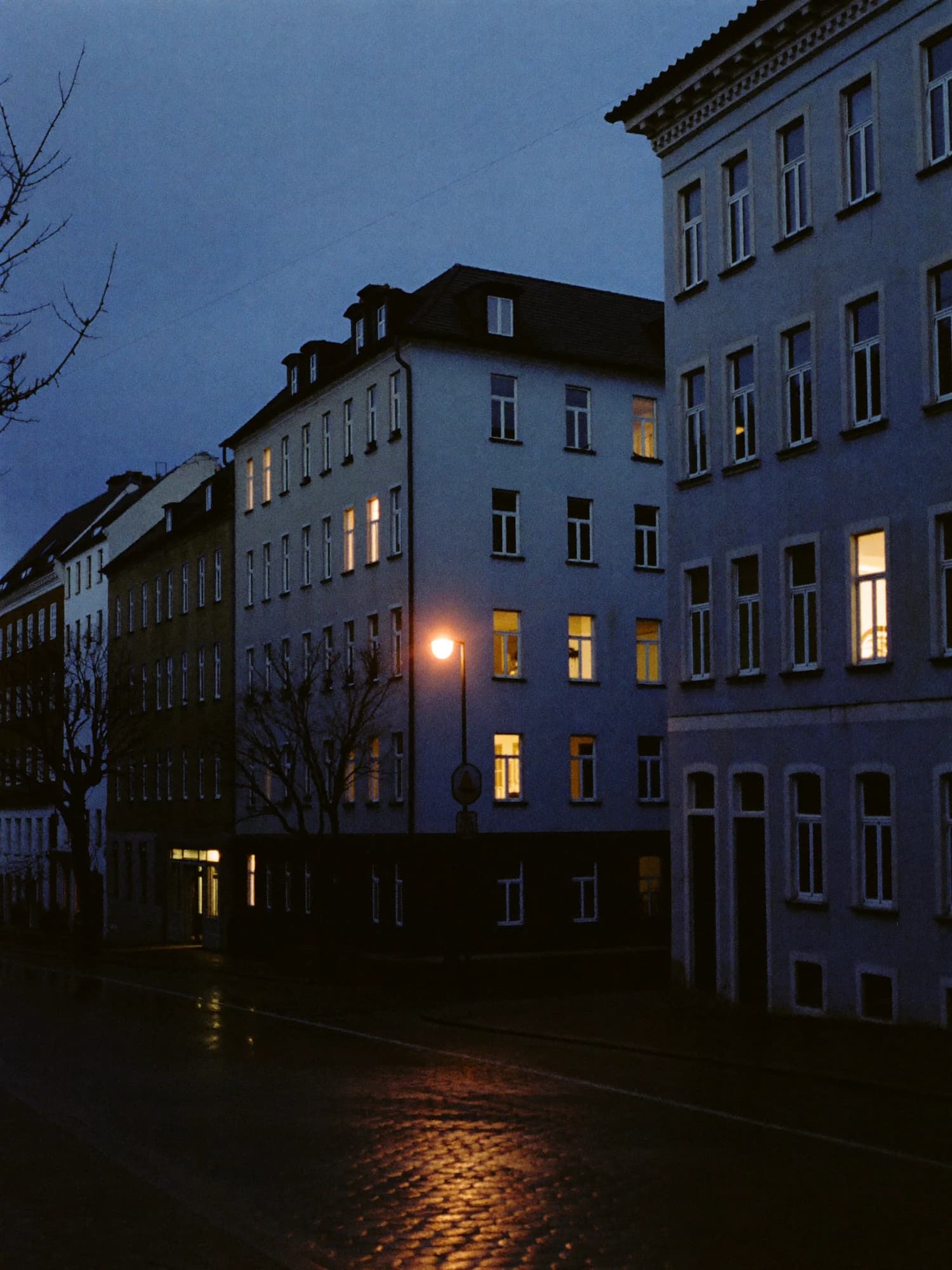 Wohnstraße mit Gründerzeithäusern am Abend, beleuchtete Fenster